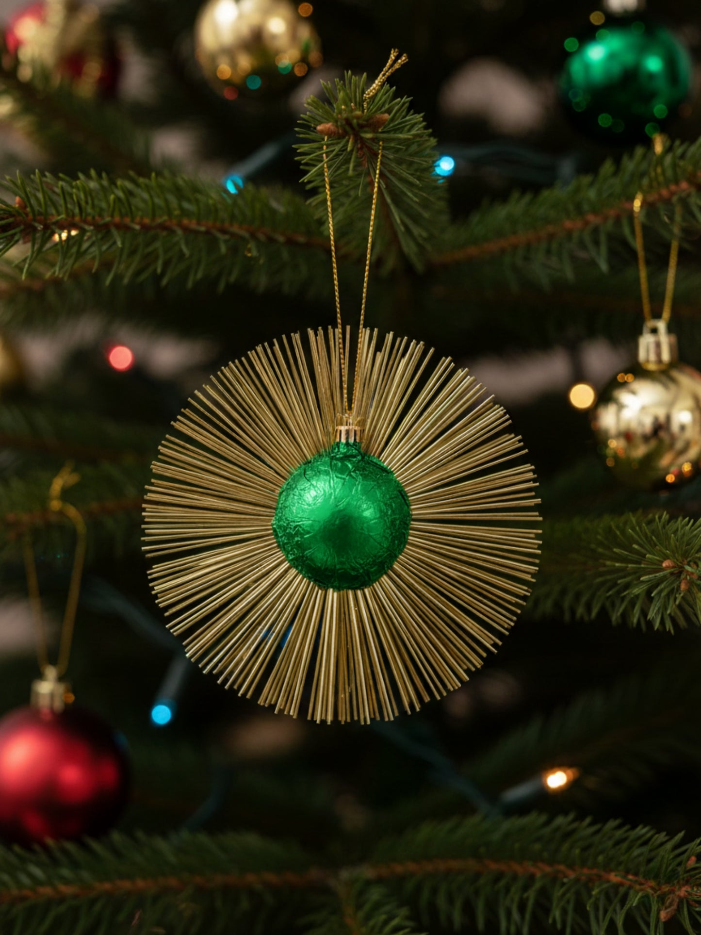 Flimmerstern in der Farbe Grün aus Vollmilchschokolade 10g mit goldenem Lametta und Aufhänger, essbare Weihnachtsdekoration aus Schokolade, Dreyer Confiserie Hameln.